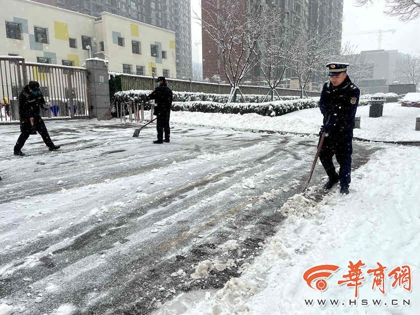 曲江新区城市管理和综合执法局工作人员正在各个学校外清理积雪 .jpg