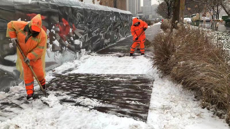 保洁人员正在清扫人行道上的积雪。