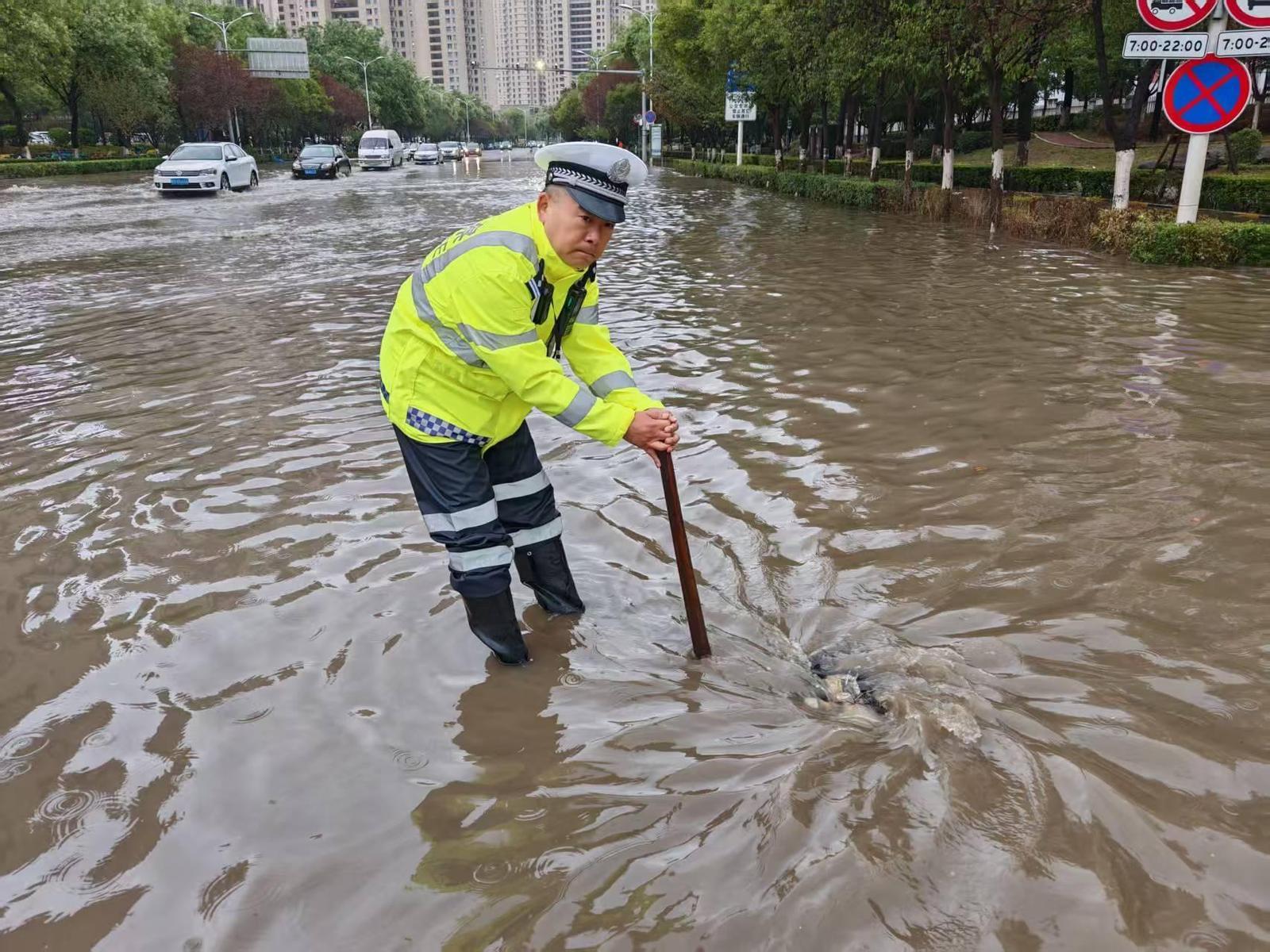 交警走进积水路段协助排水并指挥车辆