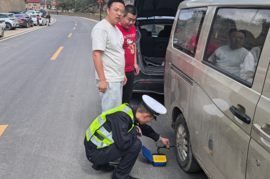 67Iq23UkArxIHezL.png 米脂县公安局杨家沟派出所民警为游客车辆轮胎充气。.png