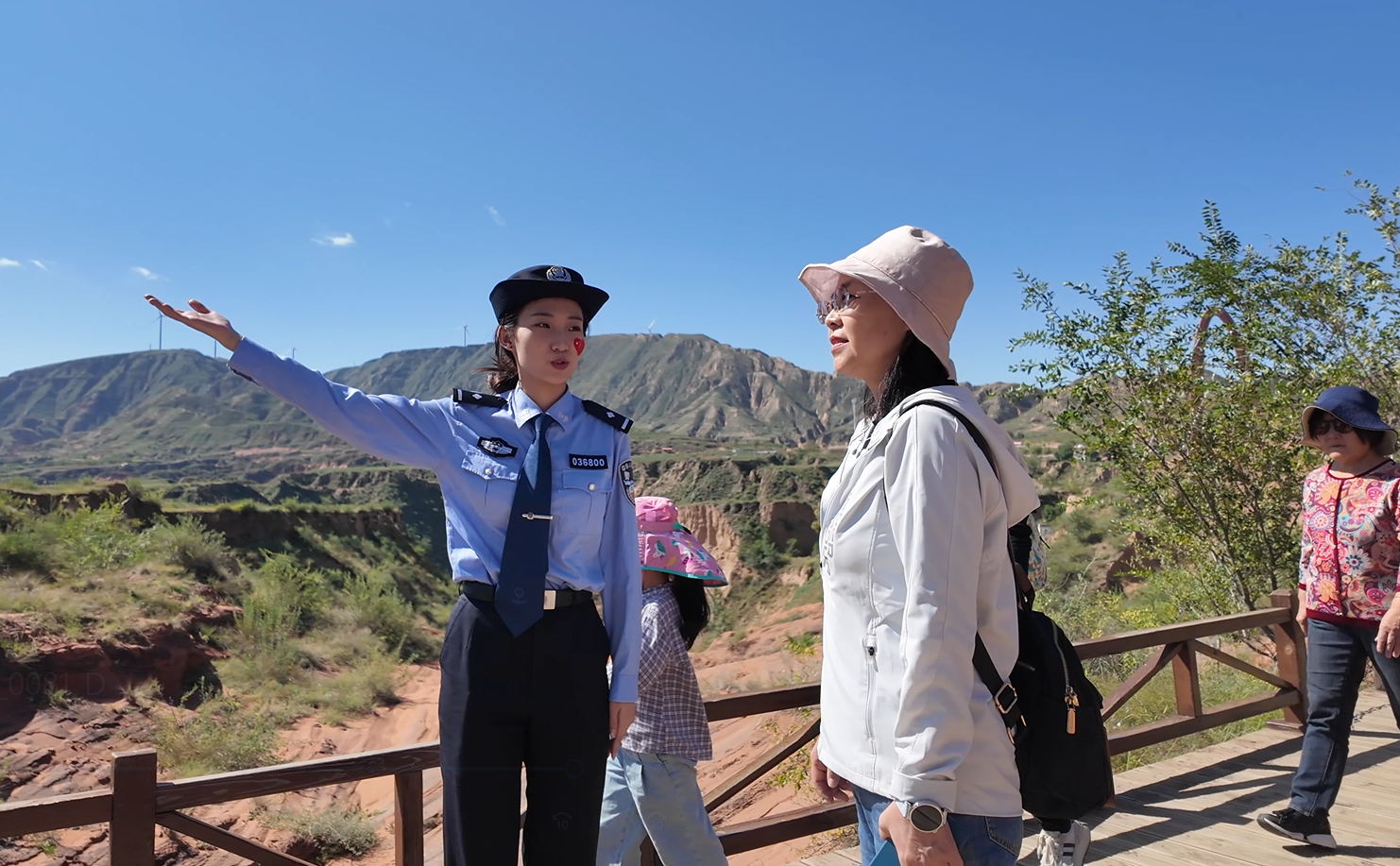 eEUENERdNVpWvi91.png 靖边县公安局民警在波浪谷丹霞地貌景区为游客指路。.png