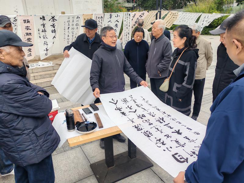 书画展现场围满了社区老年书画爱好者。