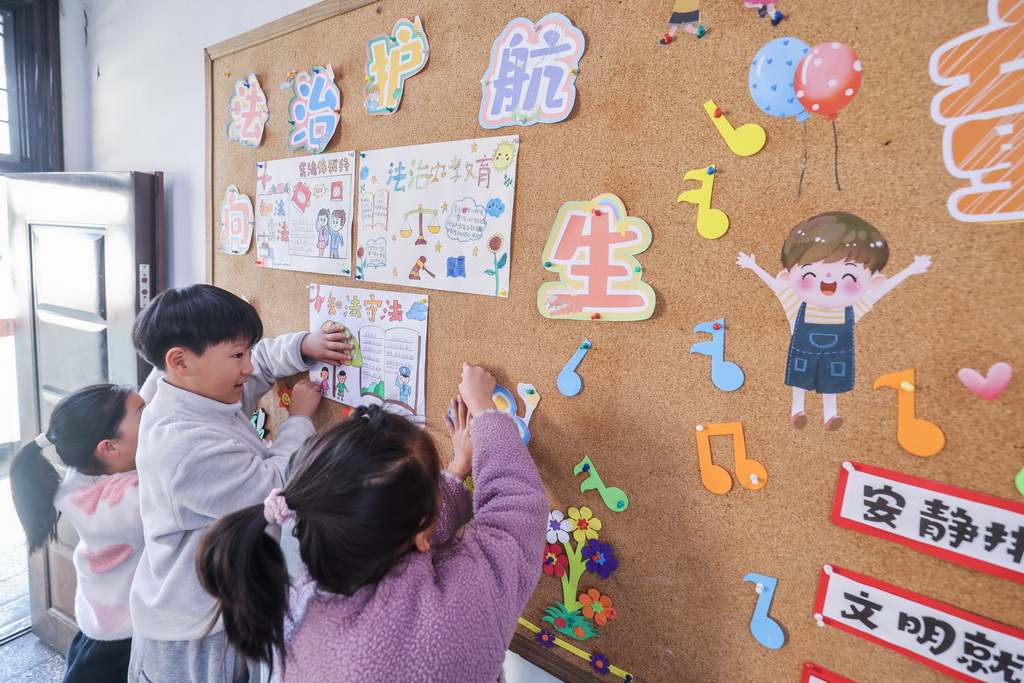 12月9日，诸暨市暨南街道中心学校王家井小学的学生把自己创作的法治宣传画贴到教室的宣传栏中。
