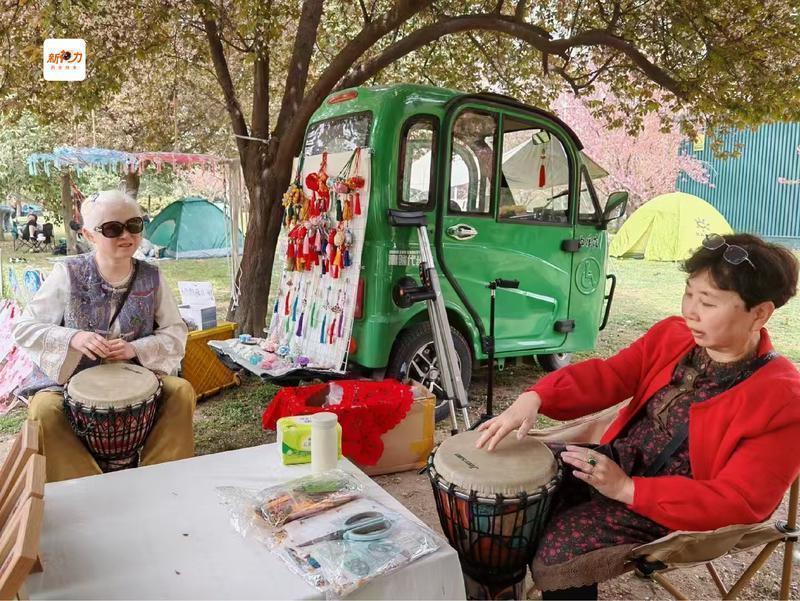 刘吟在摆摊间隙与朋友敲起非洲鼓,享受惬意的一刻。