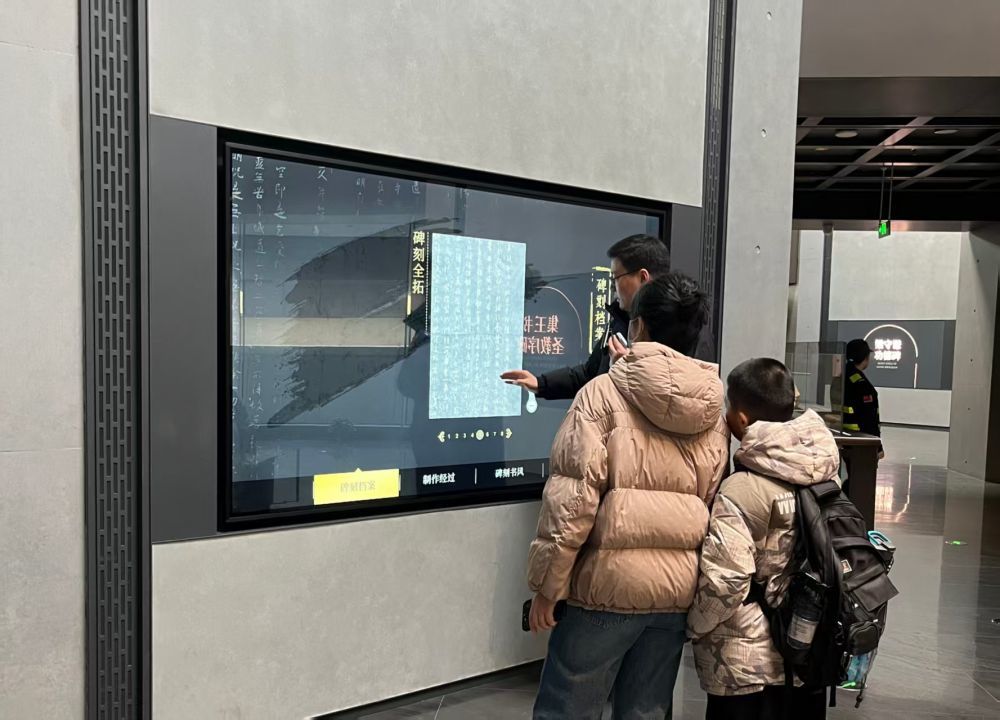 互动屏幕前，游客们正聚精会神观看碑帖。（受访者供图）