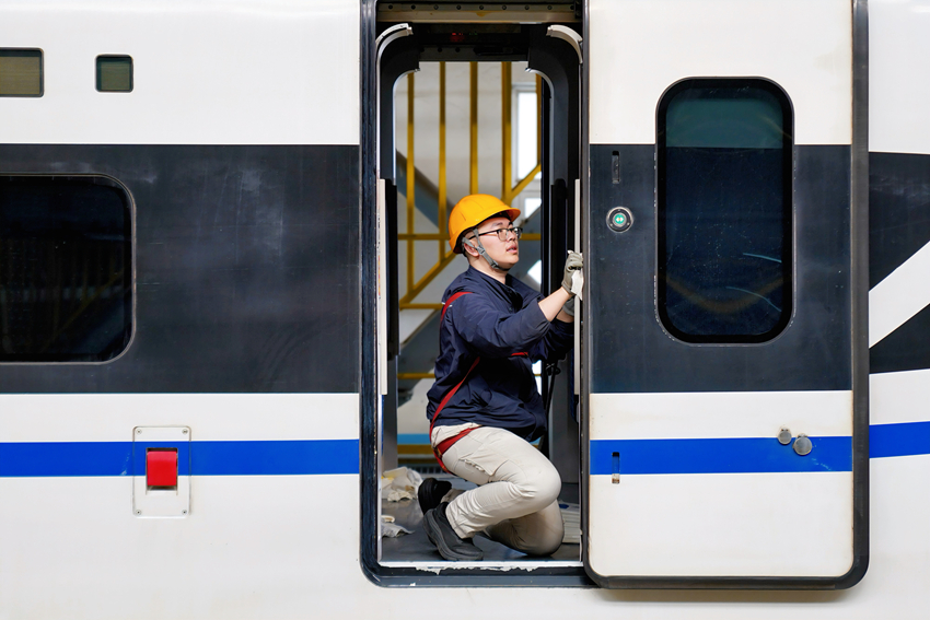 图1 图为动车组机械师邹佩岐正在对动车组车门进行清洁作业.jpg