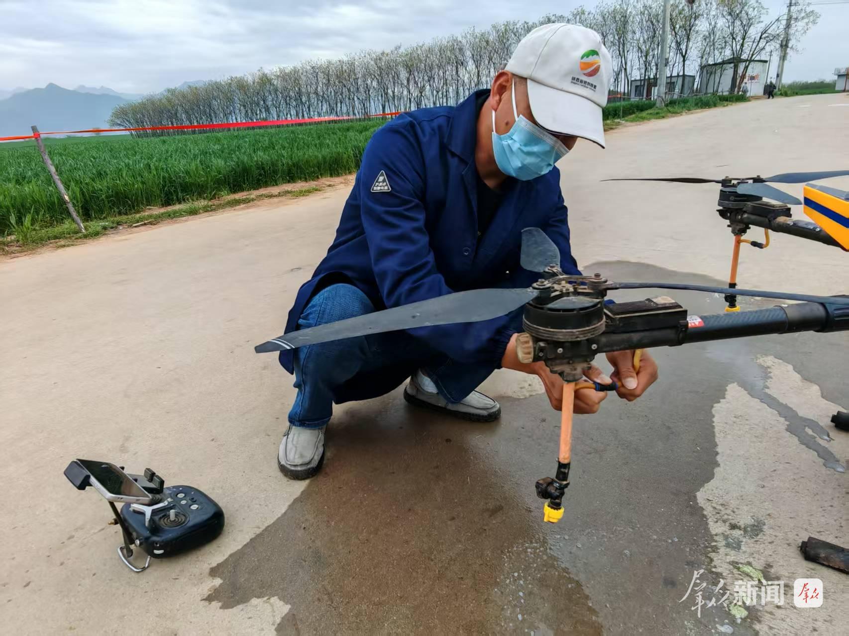 4月11日,在西安市长安区王曲街道中江兆村,长丰农机专业合作社飞手正在检查无人机设备是否正常。群众新闻记者 王海涛摄