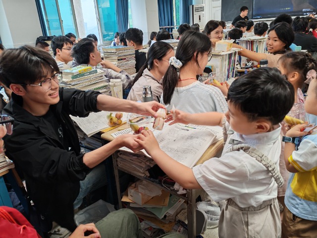 教室里高中生与小朋友们温馨互动传递食物，温情满满。忠县融媒体中心供图.jpg